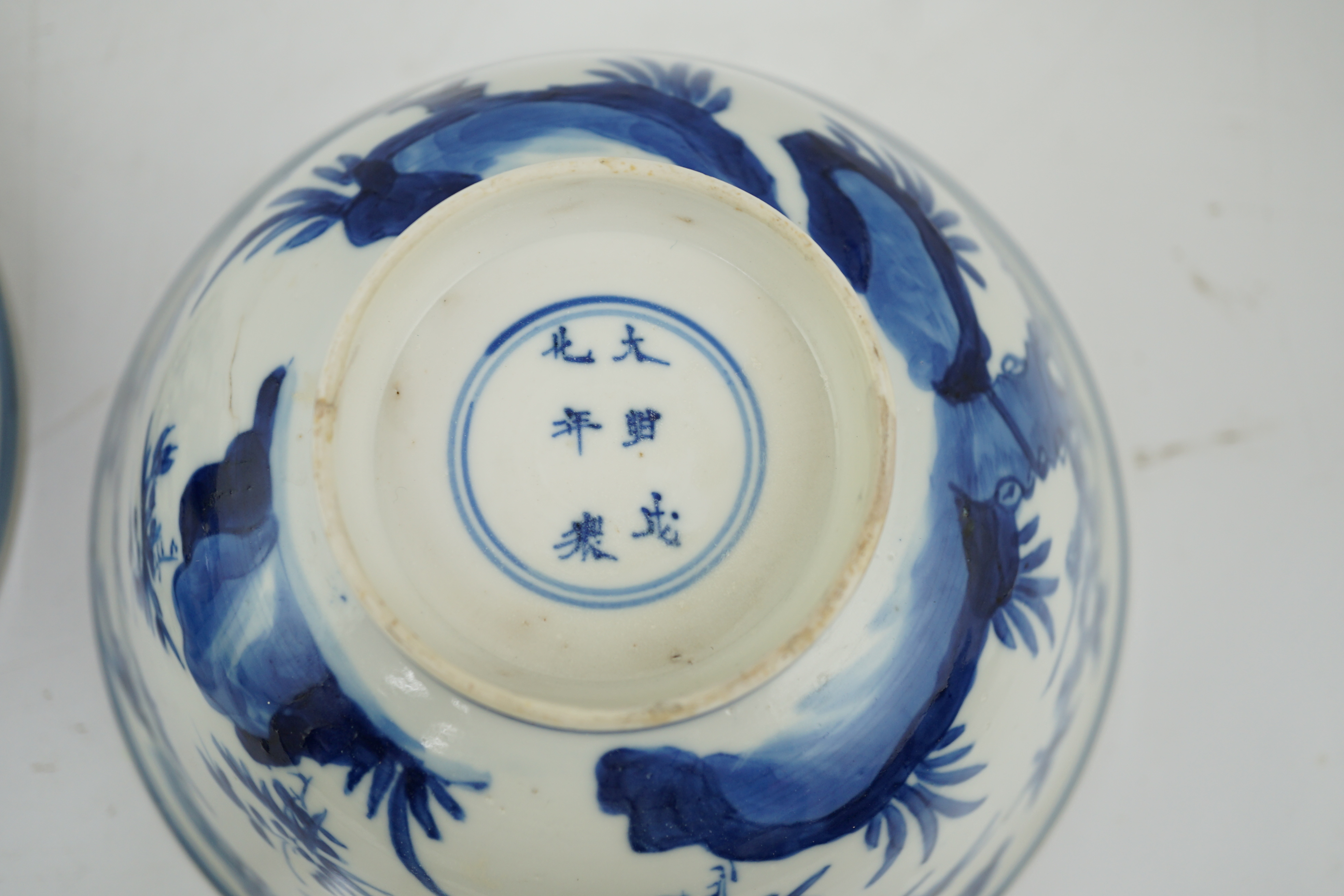 A near pair of Chinese blue and white ‘birds’ bowls, Kangxi period, one bowl restored